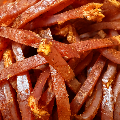 Macro view of handcrafted Spicy Pork Jerky Strips made from pork loin with smoky seasoning and chili spices.
